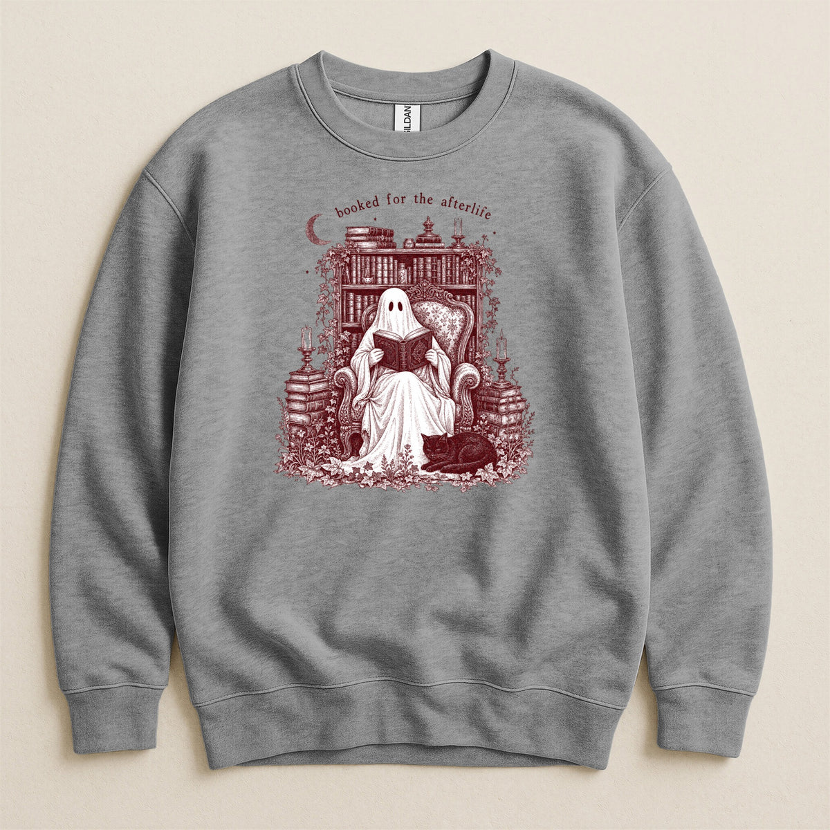 Ghost reading book with cat, "booked for the afterlife" text, on grey sweatshirt.