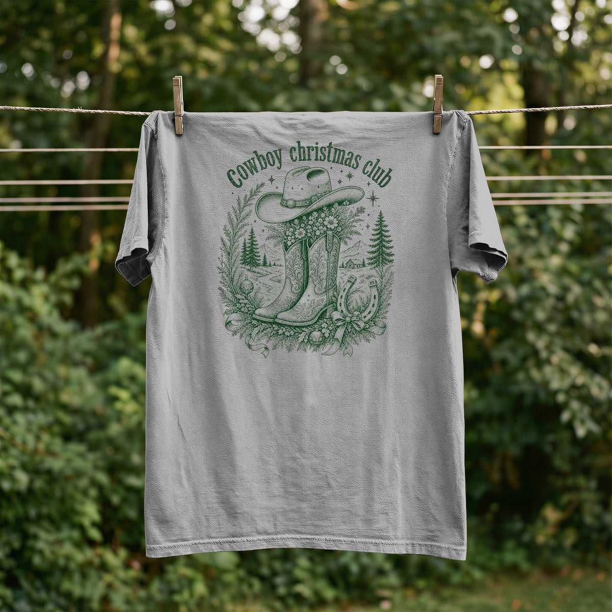 Grey t-shirt with green "Cowboy christmas club" text, cowboy hat, boots, and horseshoe graphic.