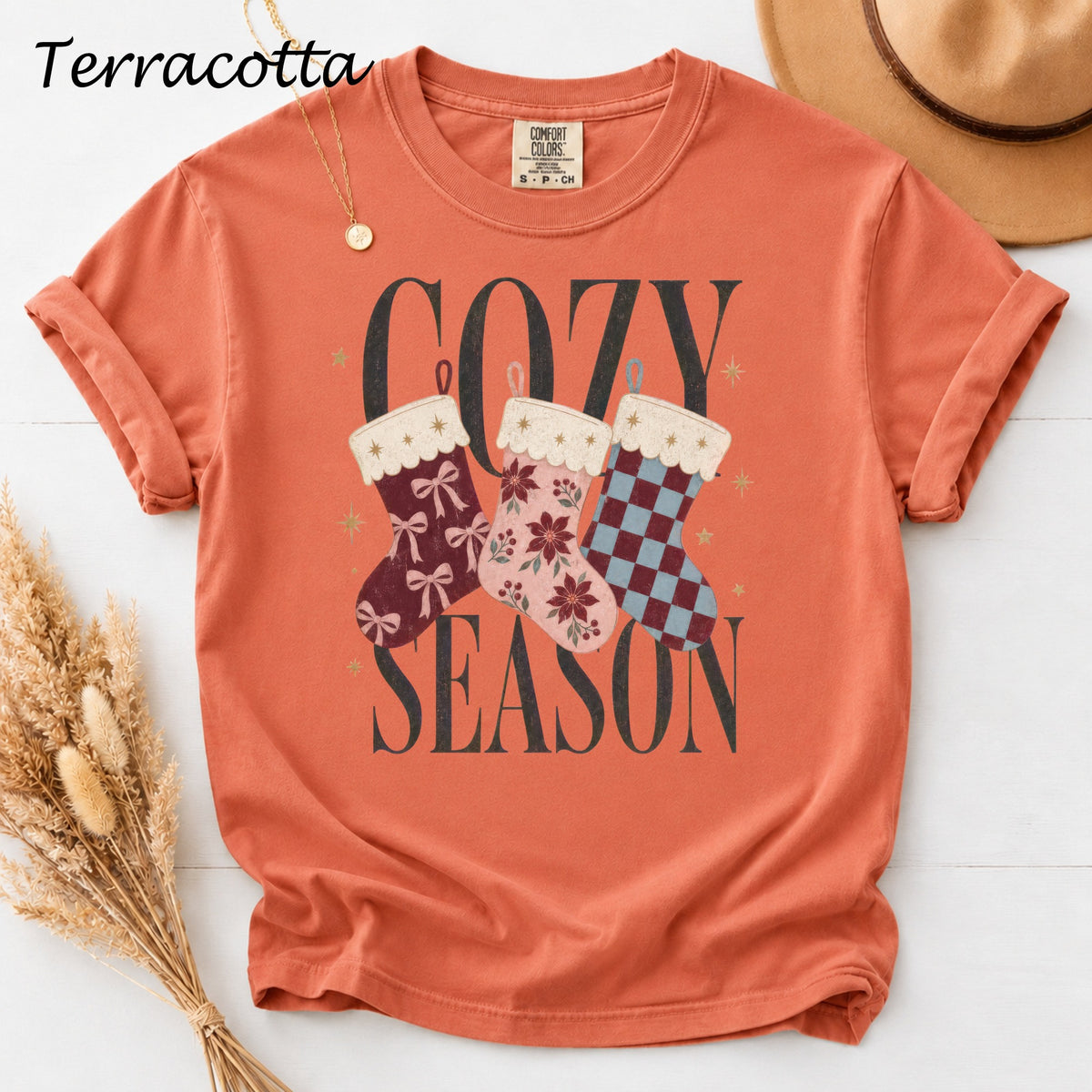 Terracotta t-shirt with "COZY SEASON" and three decorated Christmas stockings.