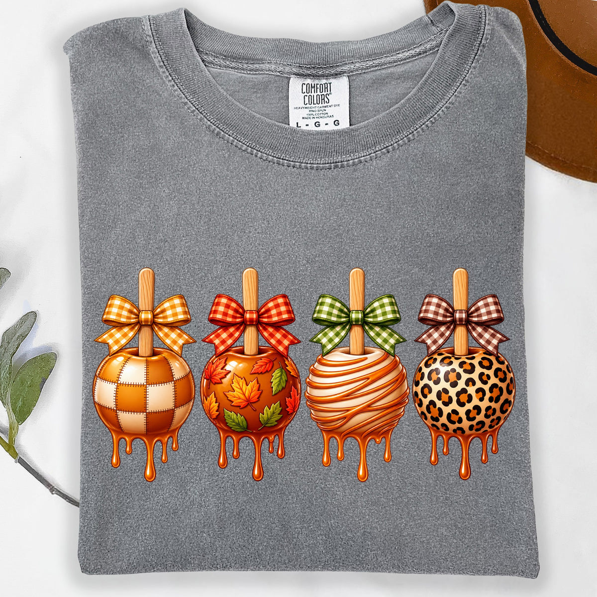 Gray t-shirt with four dripping candy apples with bows and patterned designs.