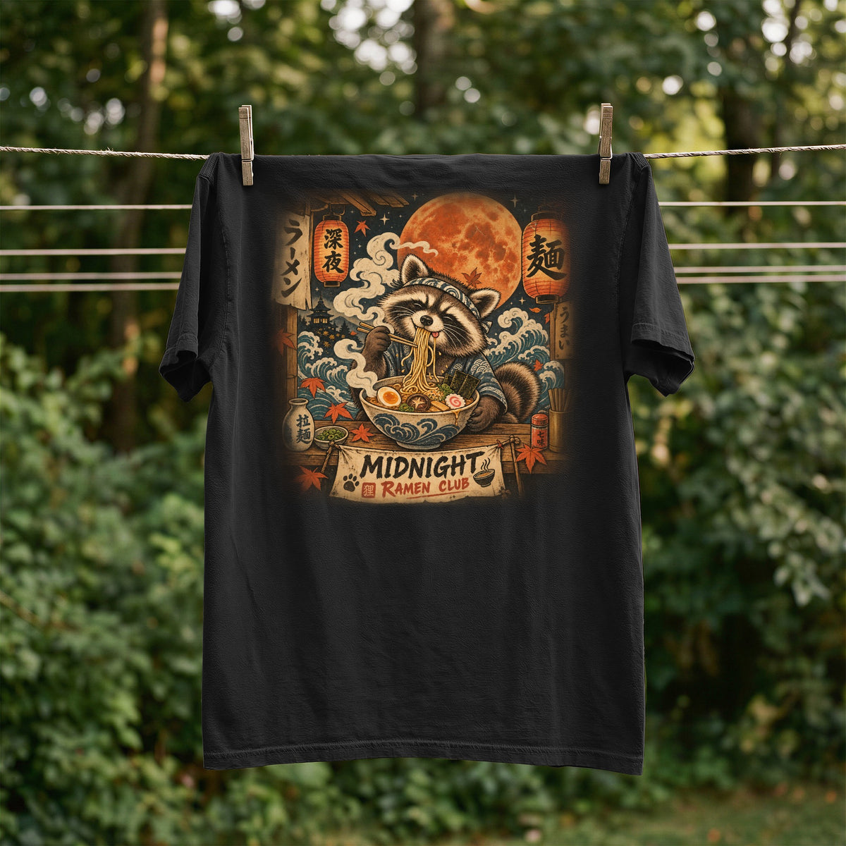 T-shirt with raccoon eating ramen under a large moon, text reads Midnight Ramen Club.