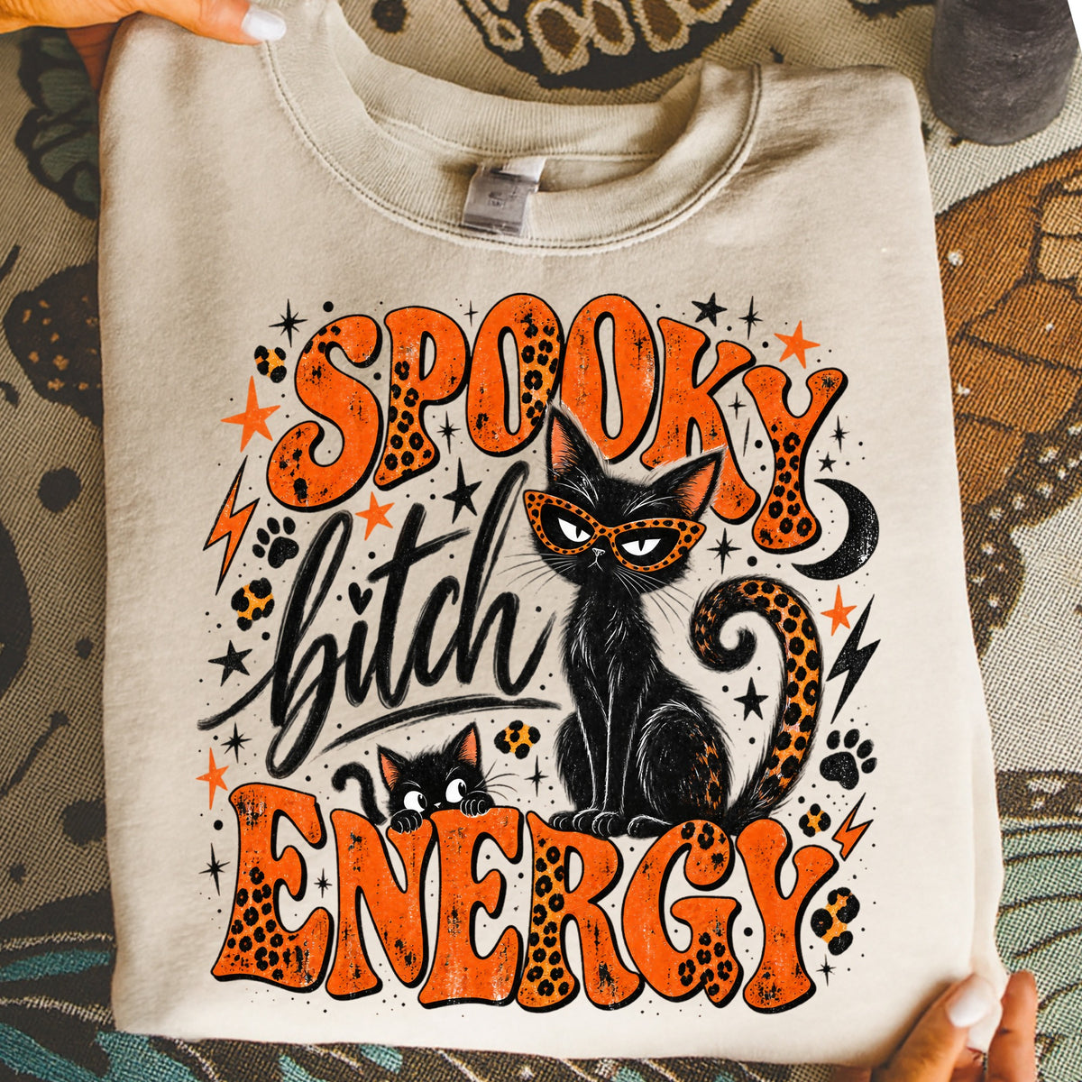 Black cat with sunglasses and text "Spooky Bitch Energy" on a cream sweatshirt.