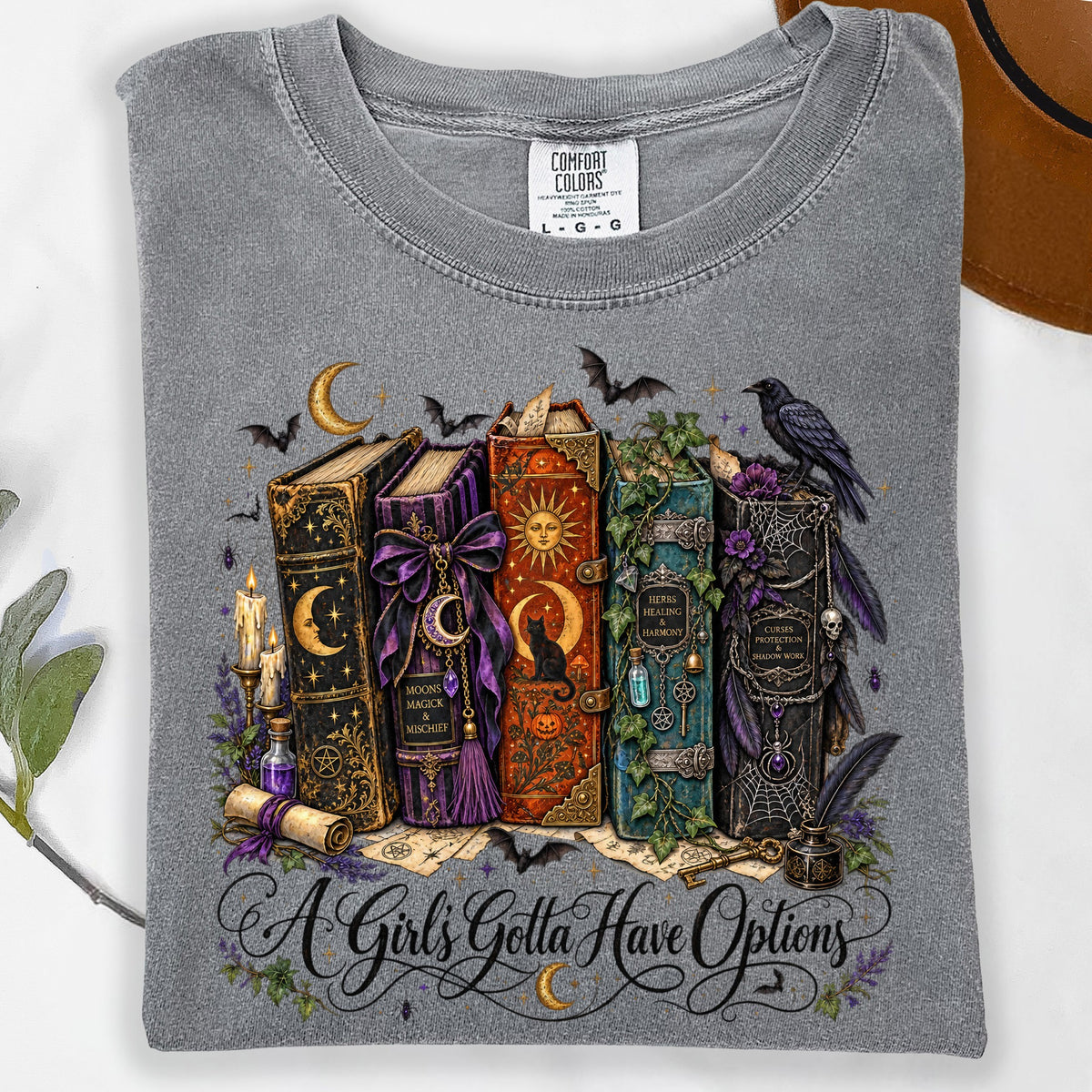 Grey t-shirt with magical books, bats, crow, and "A Girl's Gotta Have Options" text.