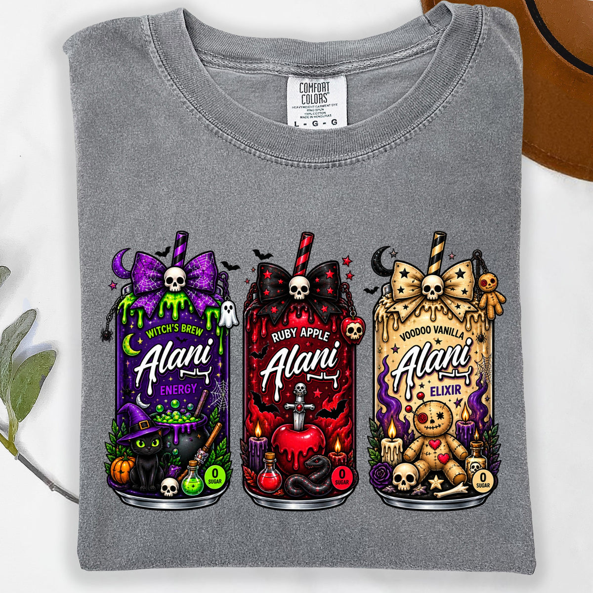 Grey t-shirt with three Halloween-themed Alani drink cans: Witch's Brew, Ruby Apple, Voodoo Vanilla.