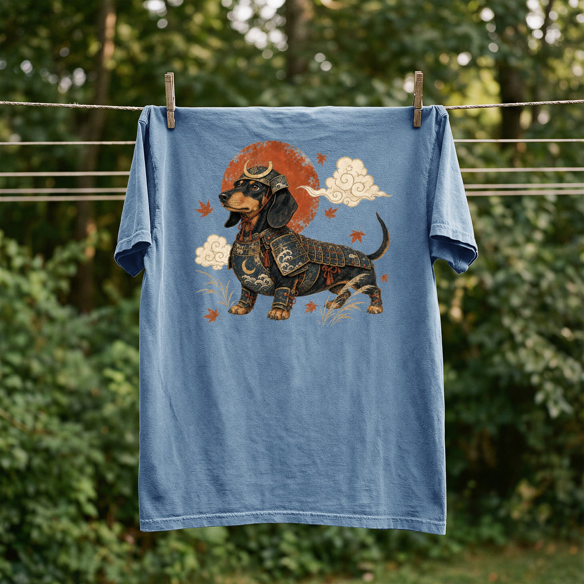 Blue t-shirt with dachshund in samurai armor graphic, hanging on clothesline.