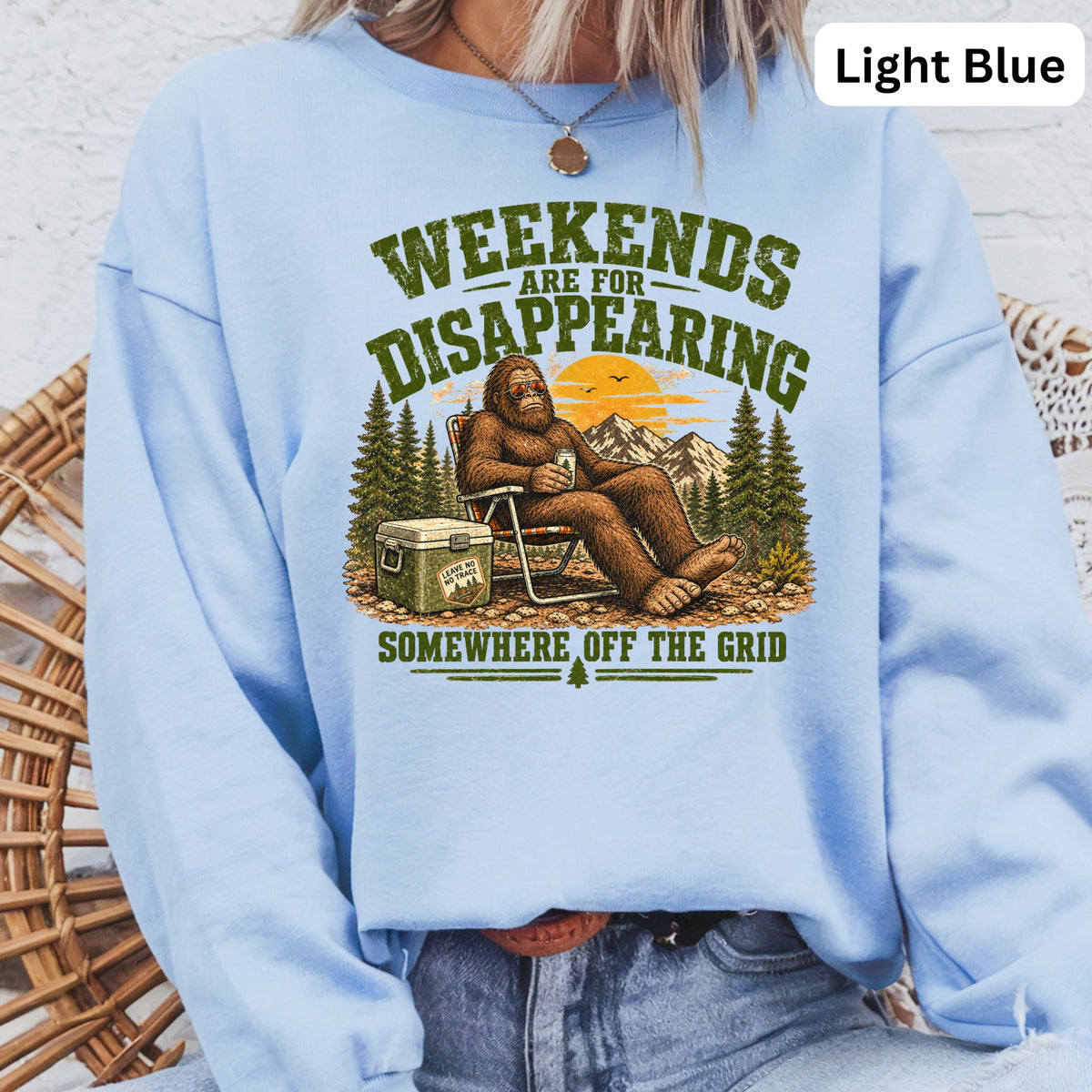Bigfoot relaxing with cooler and mountains, "Weekends Are For Disappearing Somewhere Off The Grid".