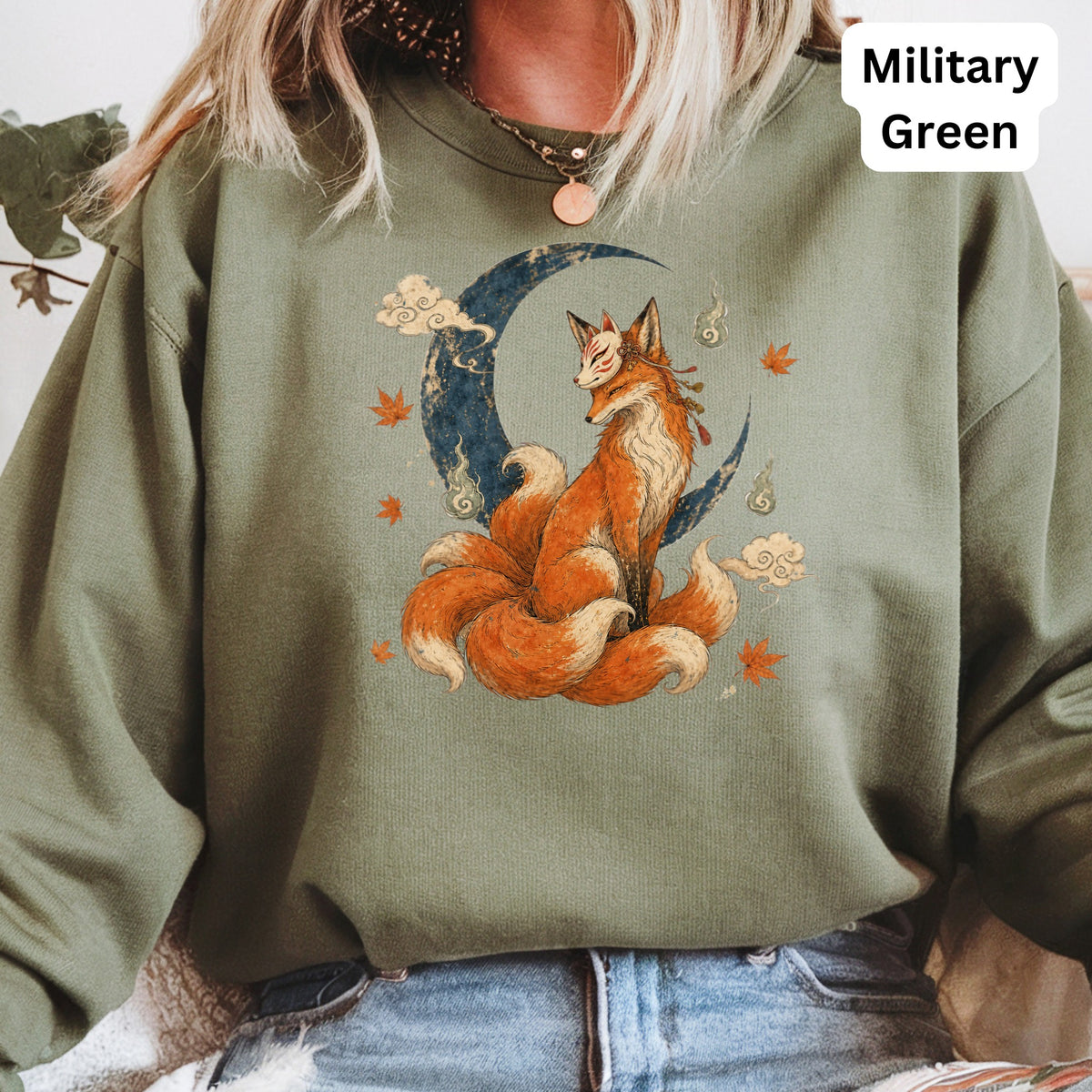 Green sweatshirt featuring a kitsune sitting on a crescent moon with clouds.