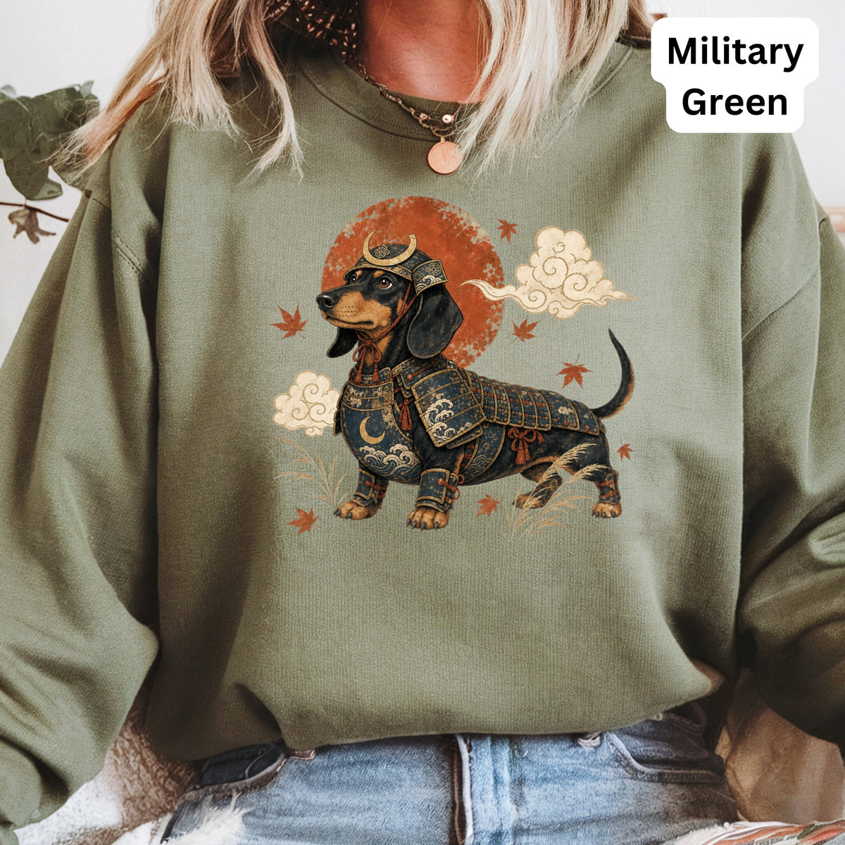 Dachshund wearing samurai armor with Japanese-inspired art on a military green sweatshirt.
