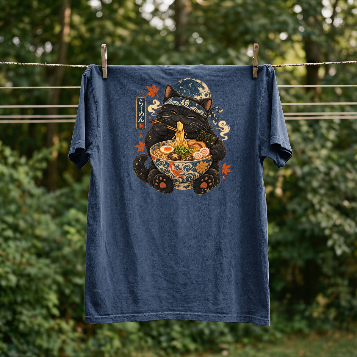 Black cat with bandana eating ramen, with Japanese text "ramen" on a blue t-shirt.