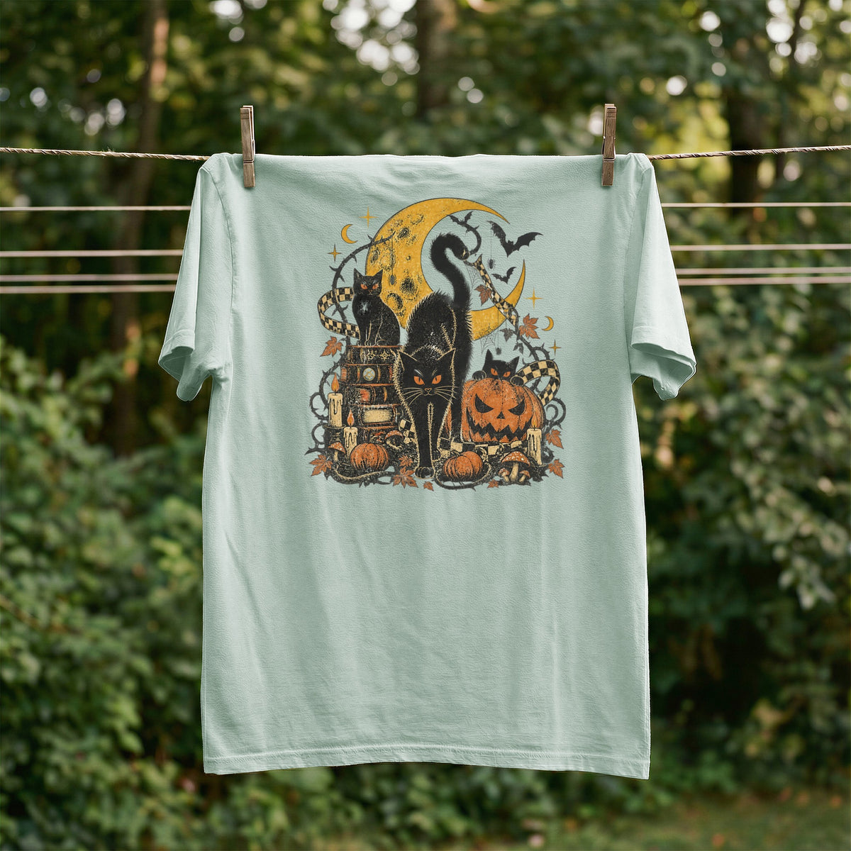 Light blue t-shirt with Halloween graphic of black cats, moon, pumpkins, and bats.