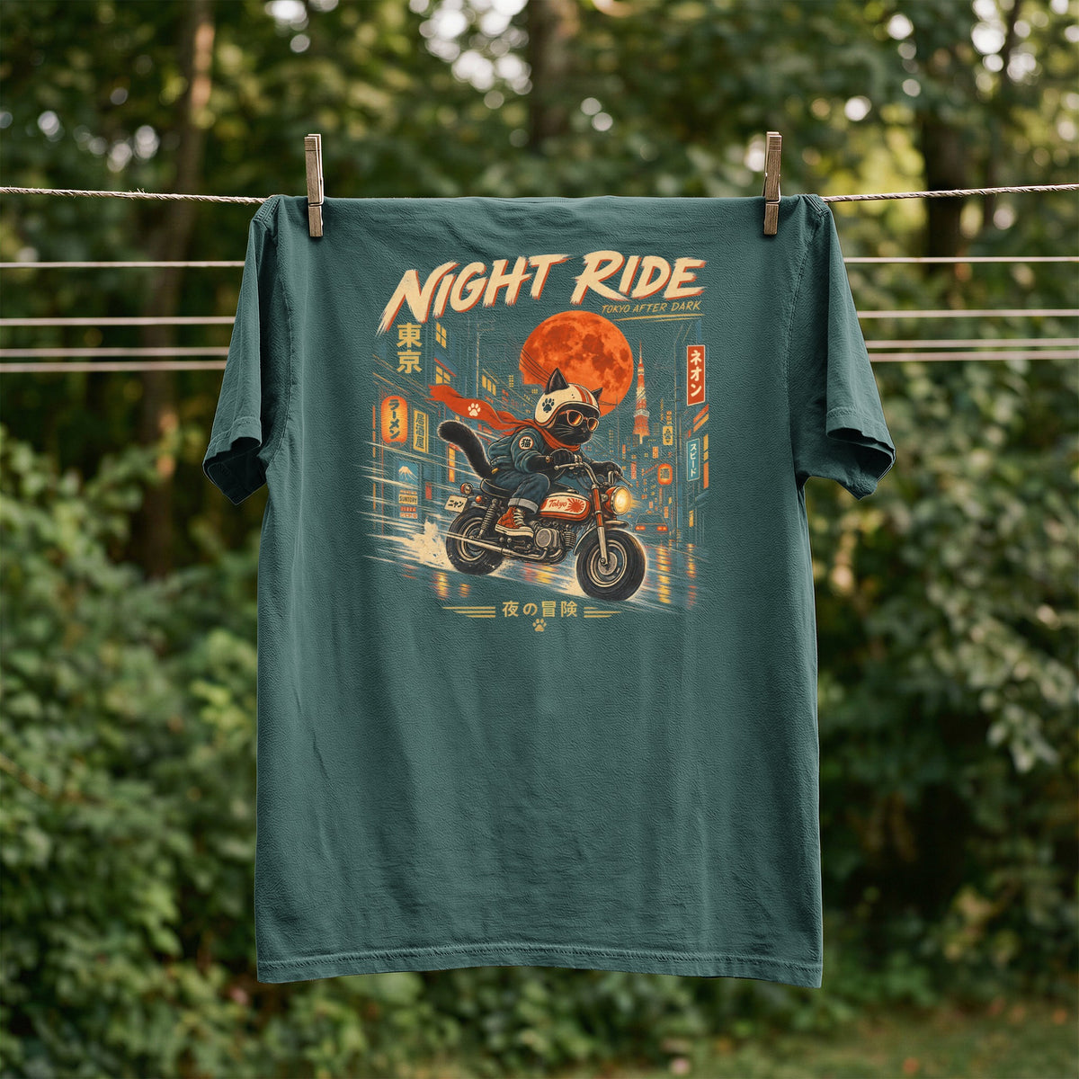 Green t-shirt with a black cat wearing a helmet riding a motorcycle through Tokyo at night.