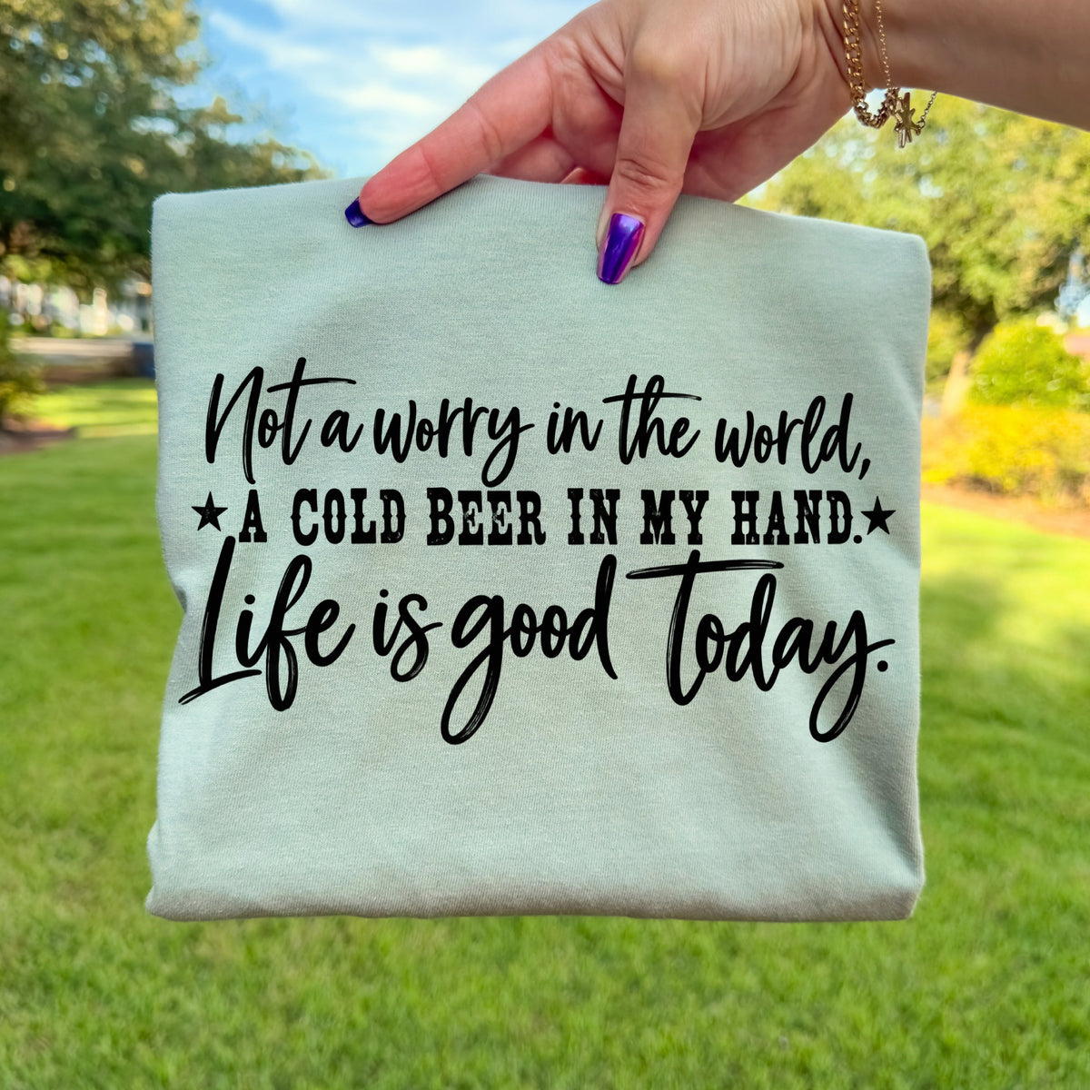 Light green t-shirt with black text: "Not a worry in the world, A cold beer in my hand. Life is good today."