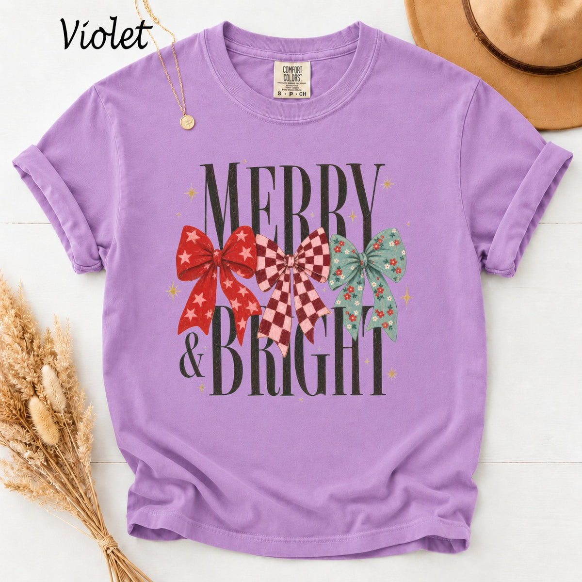 Violet t-shirt with "Merry & Bright" text and three festive bows.