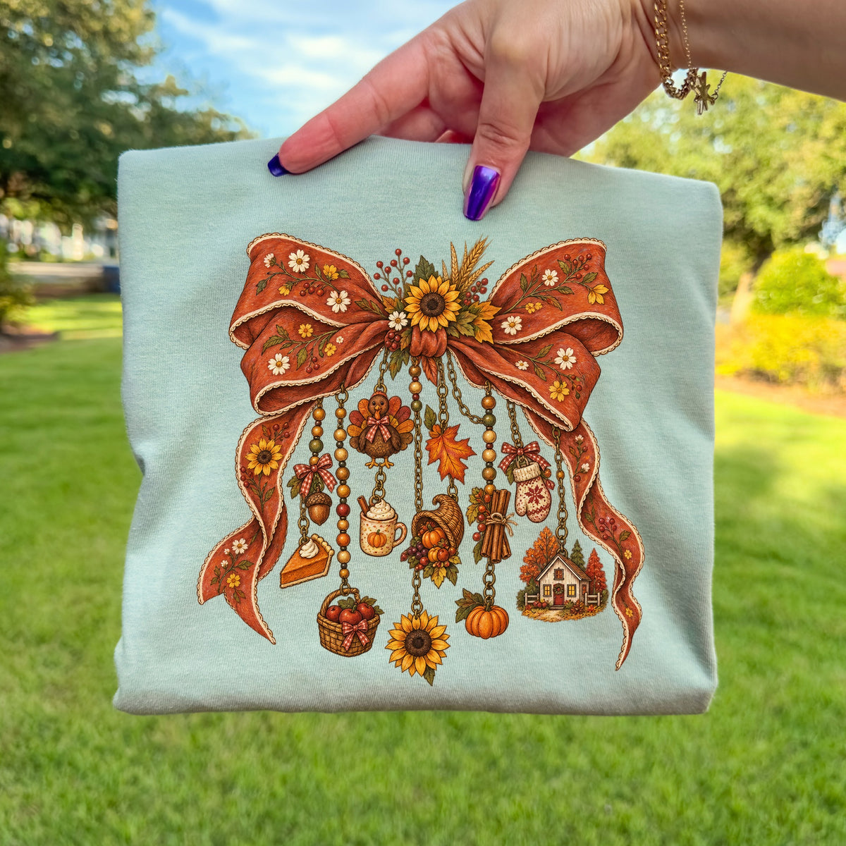 Light blue t-shirt with a vintage autumn bow graphic and hanging charms.