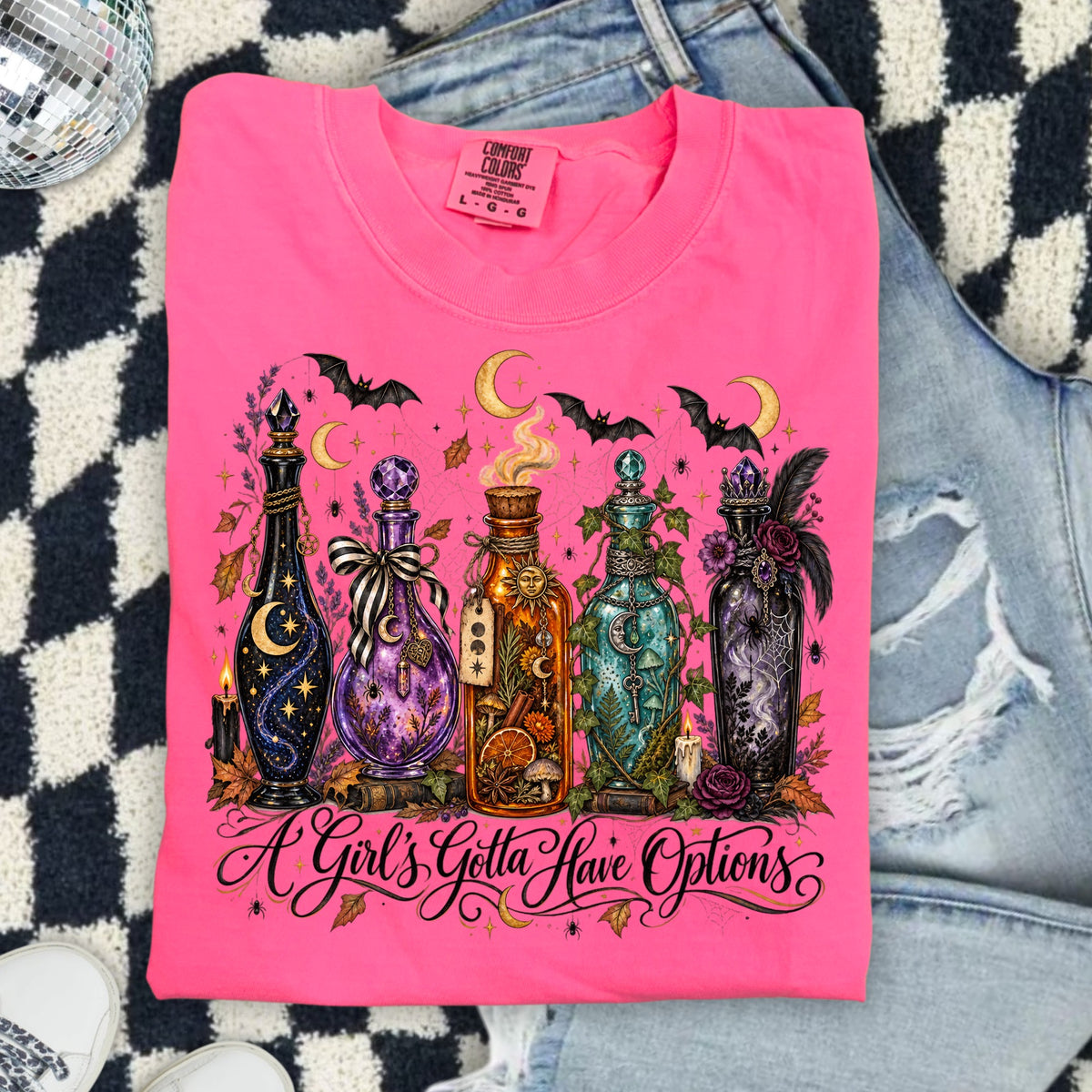Pink t-shirt with five decorative potion bottles and bats. "A Girl's Gotta Have Options" text.