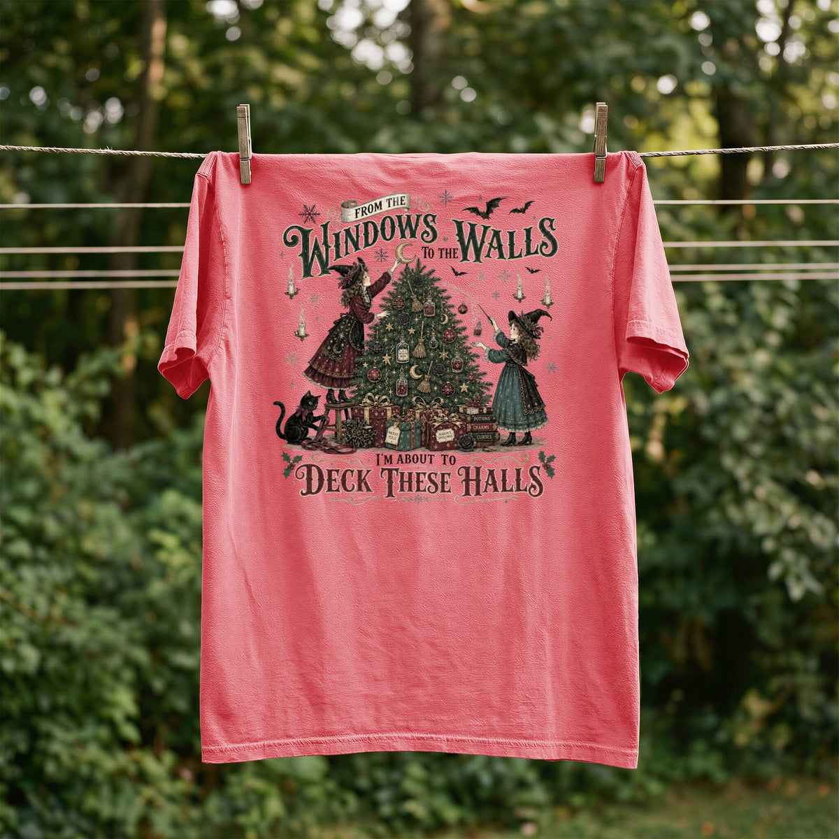 Pink t-shirt with witches, cat, and Christmas tree, reading "From the Windows to the Walls, I'm About to Deck These Halls".