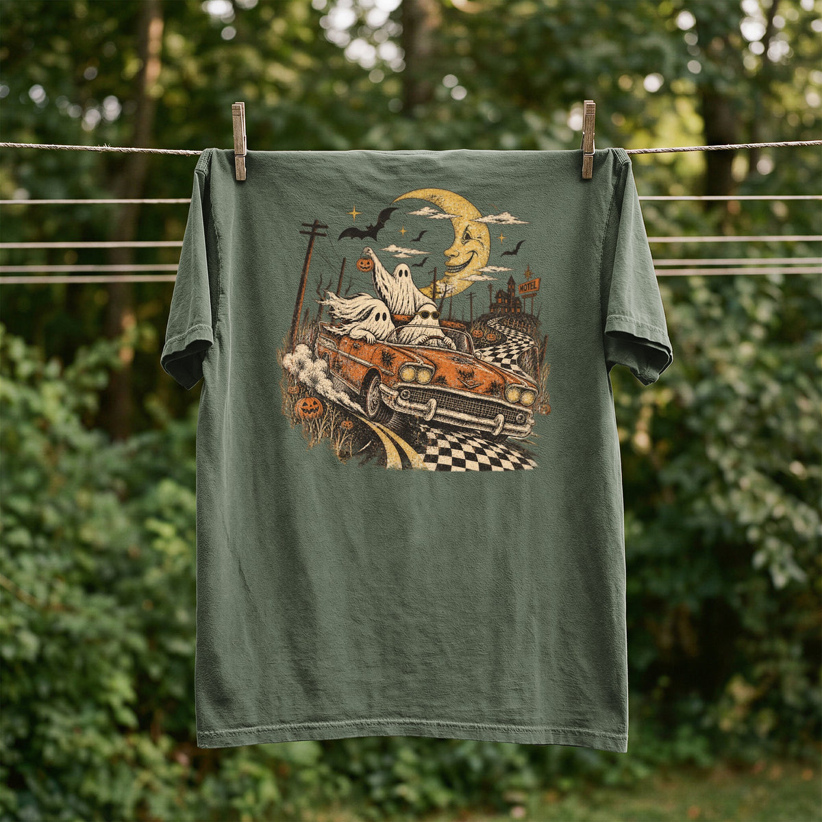Green t-shirt with graphic of ghosts in a car, a haunted motel, and a crescent moon.