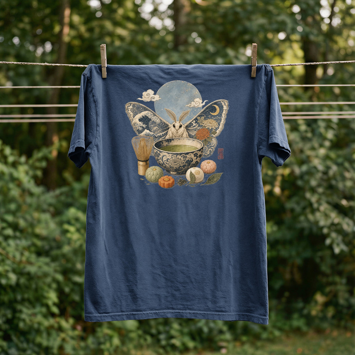 Dark blue t-shirt with a moth, moon, tea set, and mooncakes graphic.