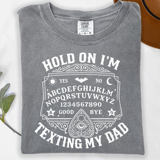 Grey t-shirt with "Hold on I'm texting my dad" and Ouija board graphic.