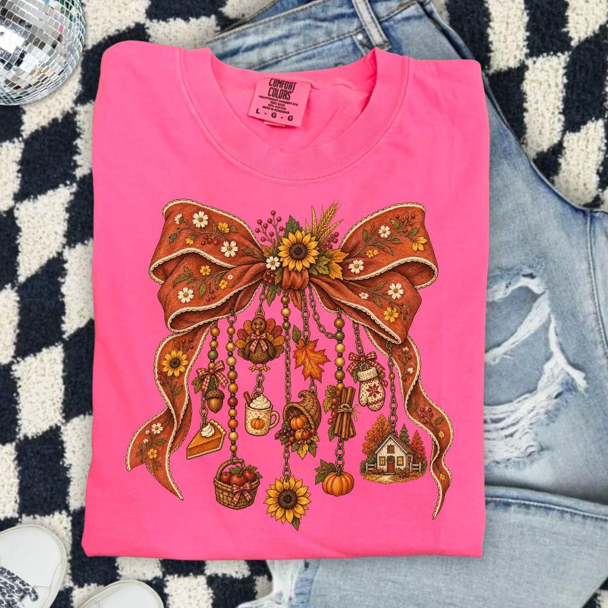 Bright pink shirt with Thanksgiving-themed graphic featuring a bow with hanging charms.