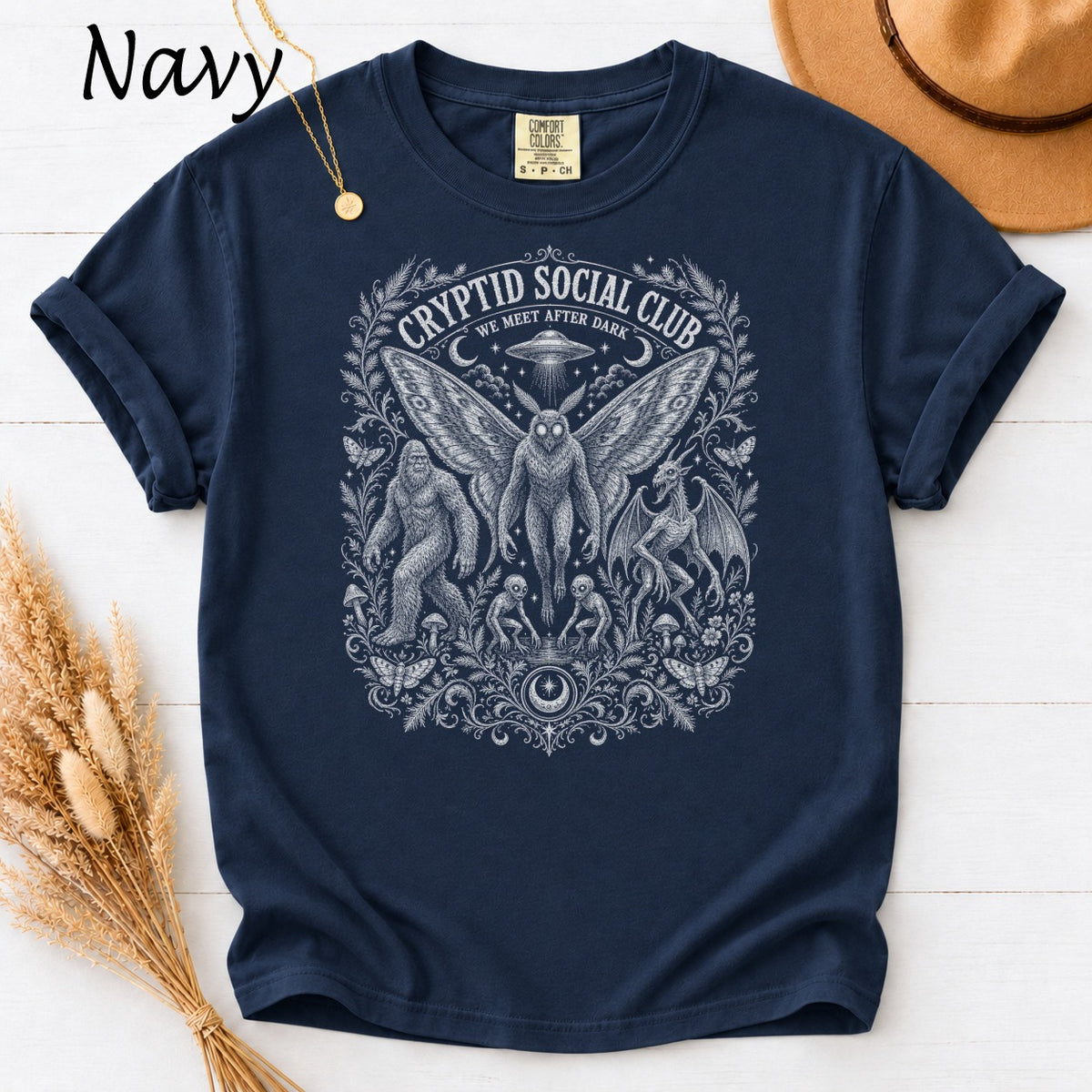 Navy t-shirt with Cryptid Social Club design featuring Bigfoot, Mothman, and a dragon.