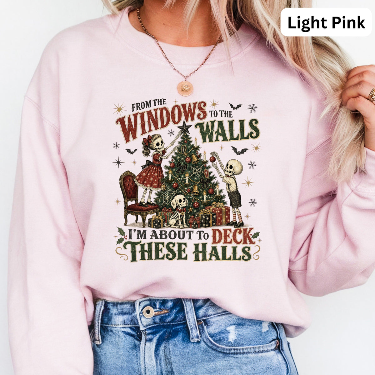 Light pink sweatshirt with skeletons decorating a Christmas tree and the text "I'm About To Deck These Halls".