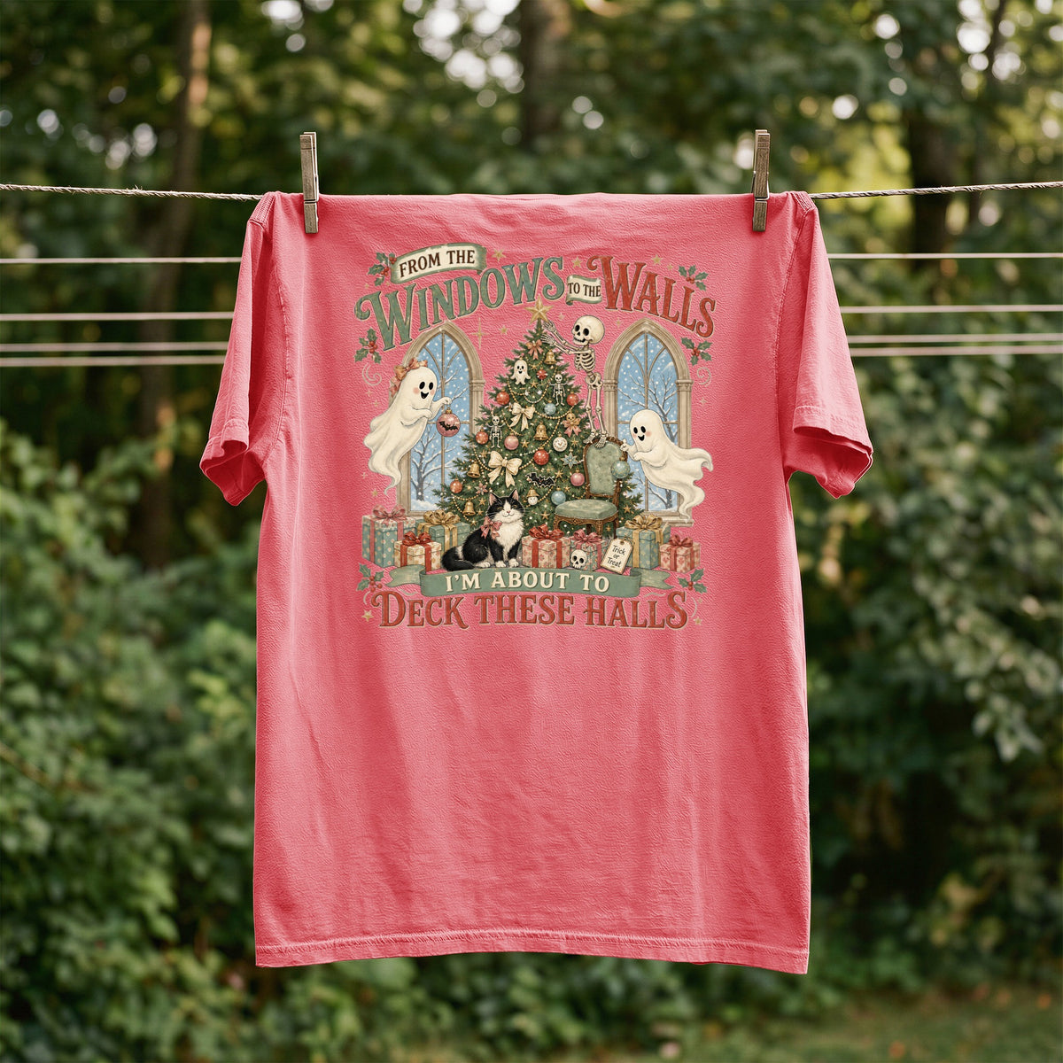 Pink shirt with spooky Christmas graphic featuring ghosts, skeleton, cat, and text.