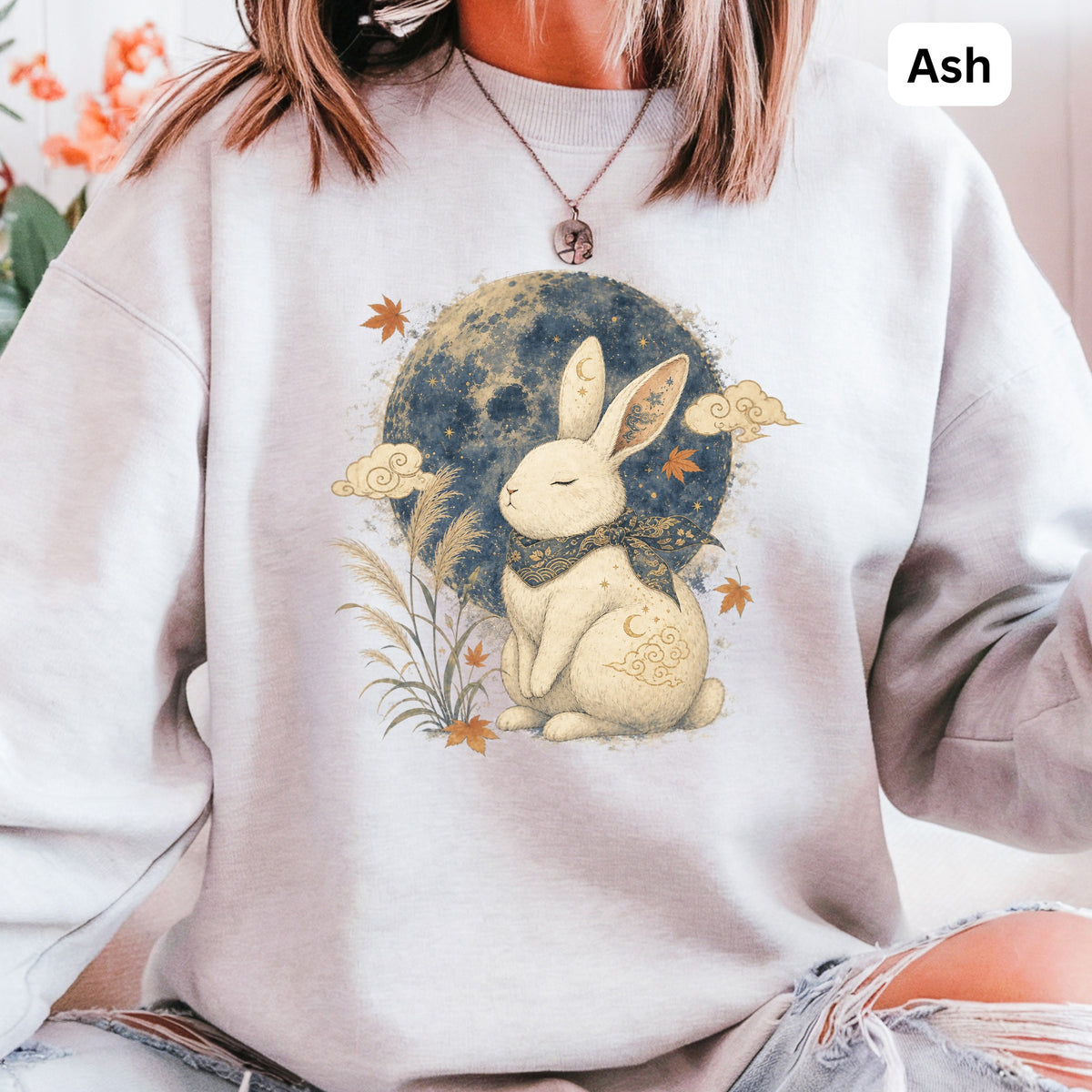 Light grey sweatshirt with a graphic of a white rabbit sitting before a moon and clouds.