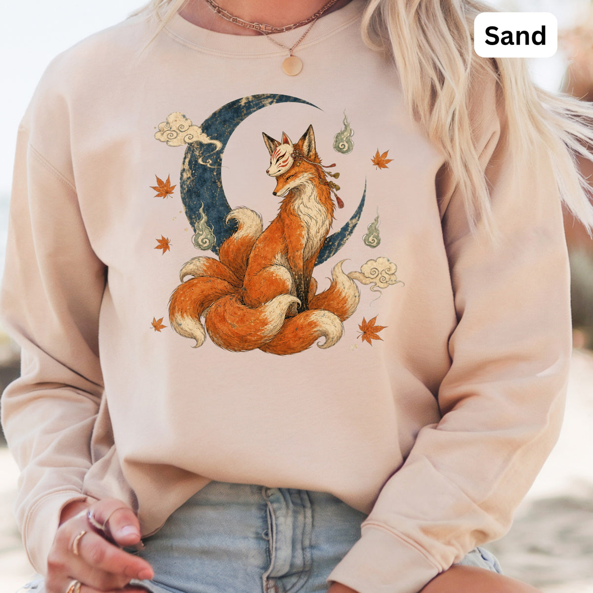 Sand colored sweatshirt with a graphic of a nine-tailed fox in front of a moon.