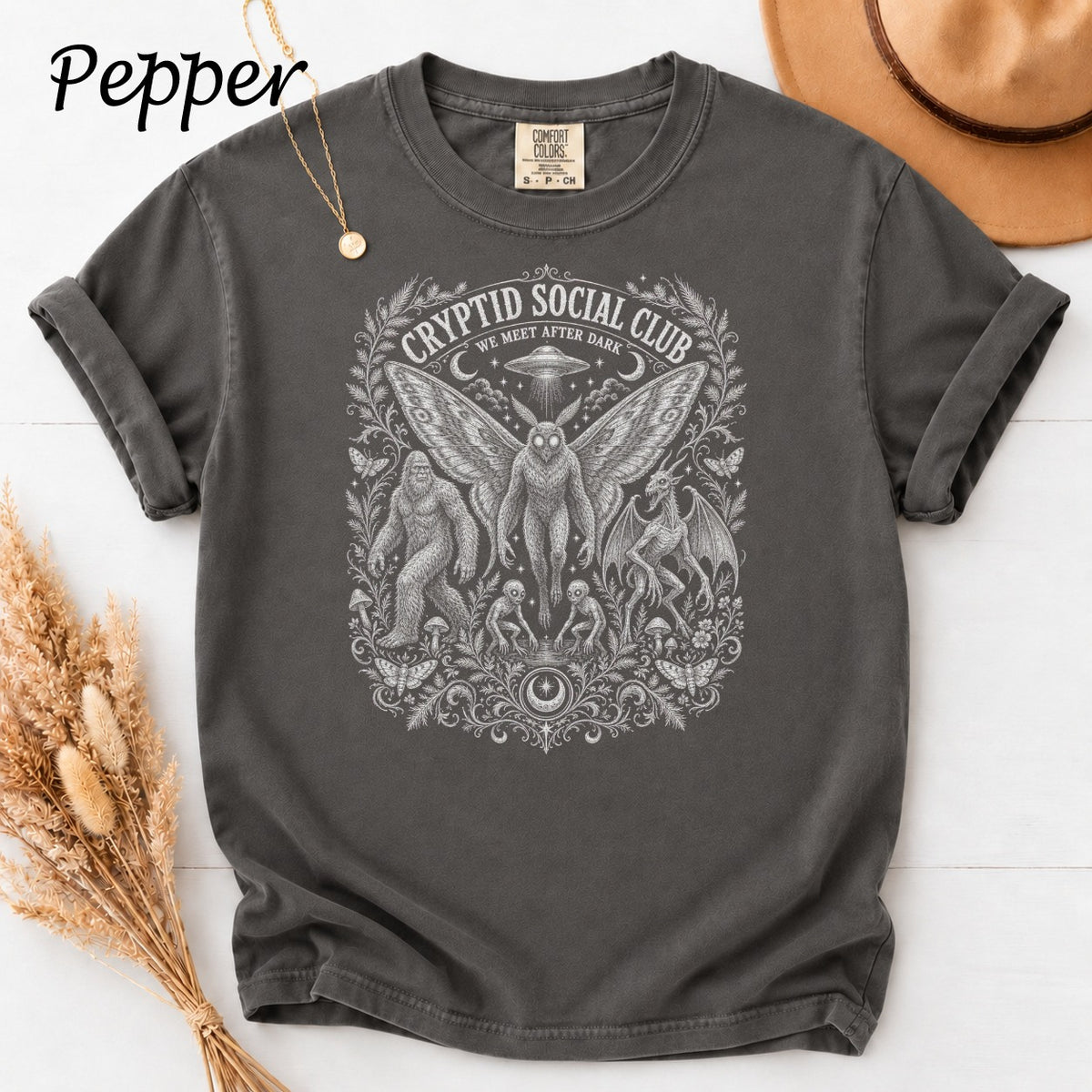 Grey t-shirt with Cryptid Social Club graphic featuring Bigfoot, Mothman, and aliens.
