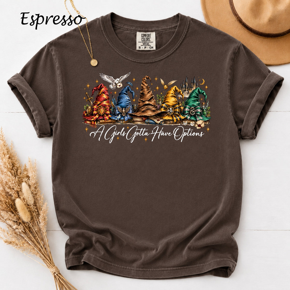 Brown t-shirt with five Hogwarts house sorting hats and text "A Girls Gotta Have Options".