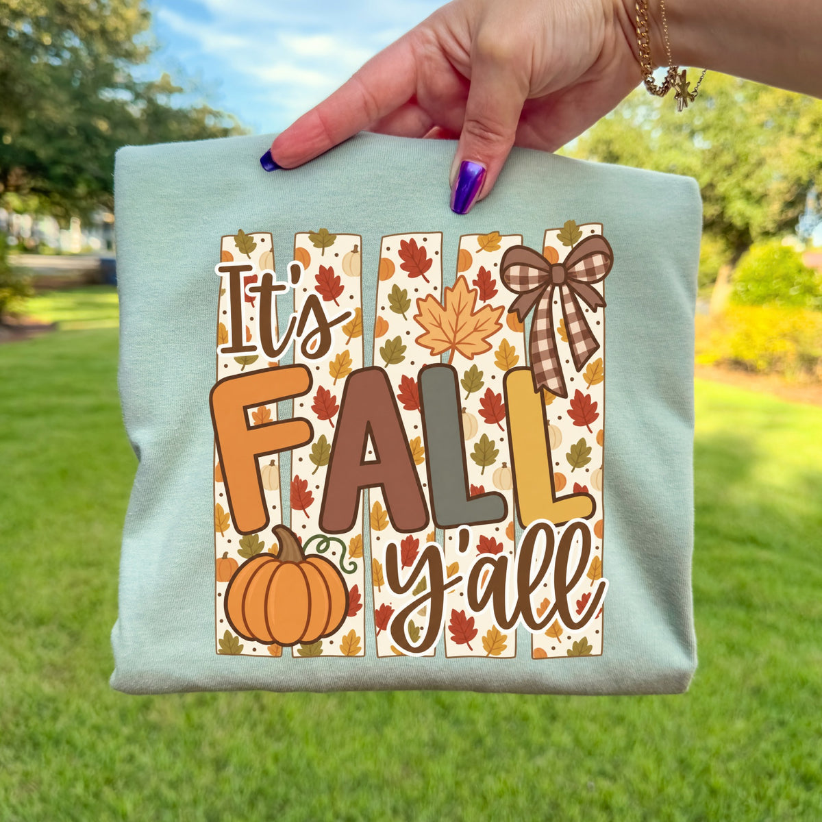 Light blue t-shirt with "It's FALL y'all" text, pumpkins, and autumn leaves design.