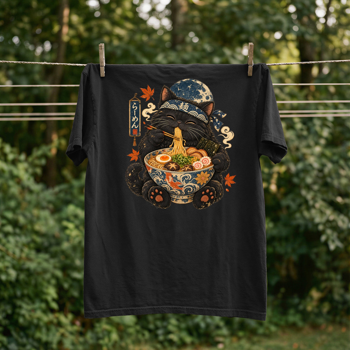 Black t-shirt with a black cat wearing a bandana eating ramen from a decorative bowl.
