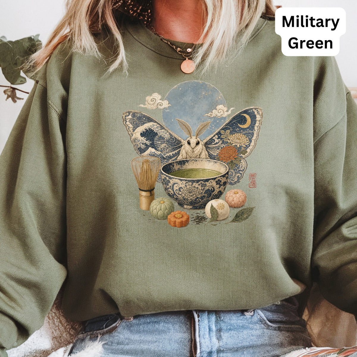 Green sweatshirt with a moth, matcha, and Japanese motifs graphic.