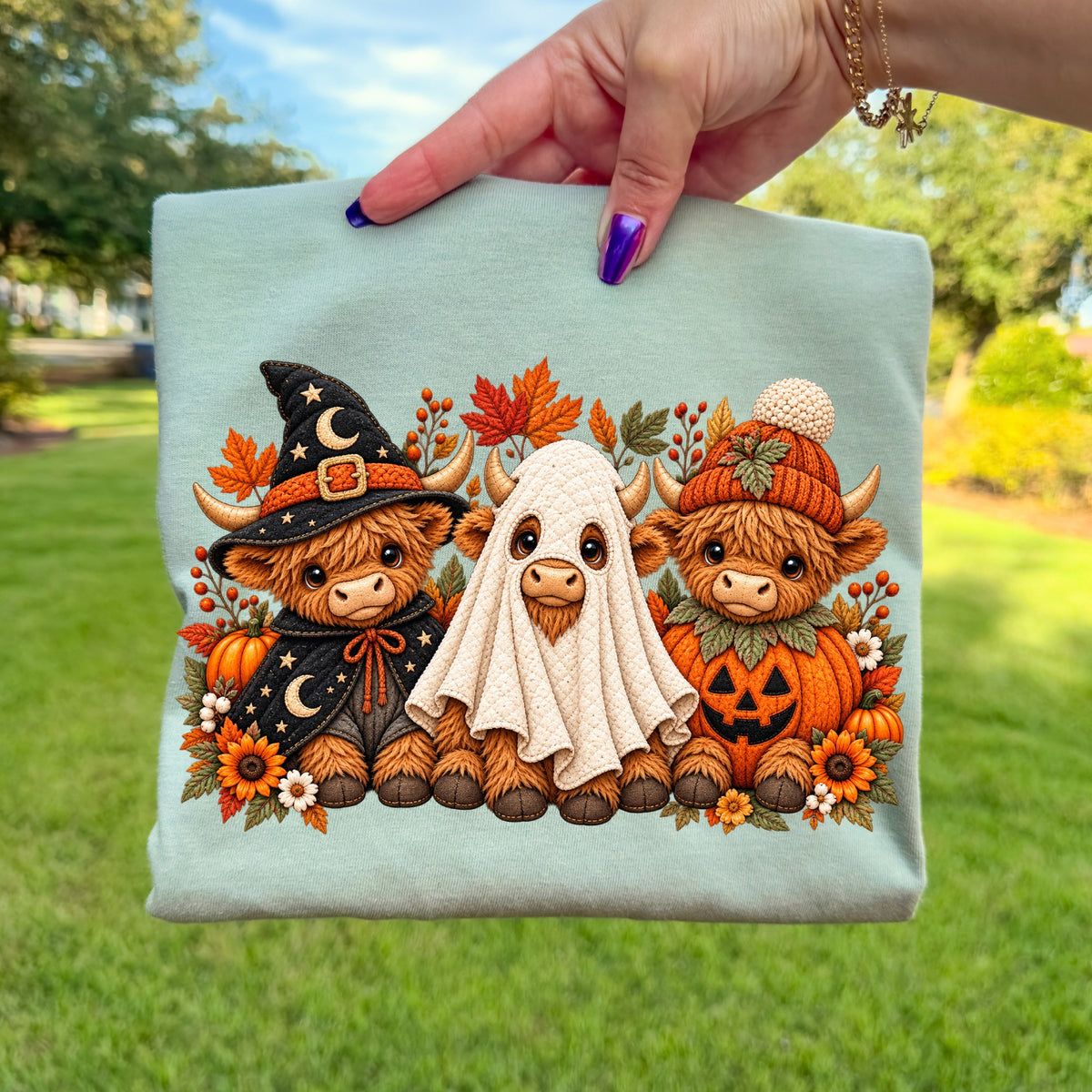 Three Highland cows in Halloween costumes: witch, ghost, and pumpkin.