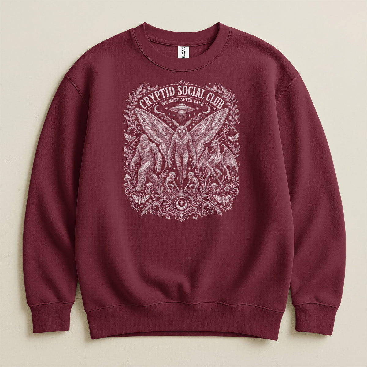 Maroon sweatshirt with Cryptid Social Club design featuring moths, Bigfoot, and UFO.
