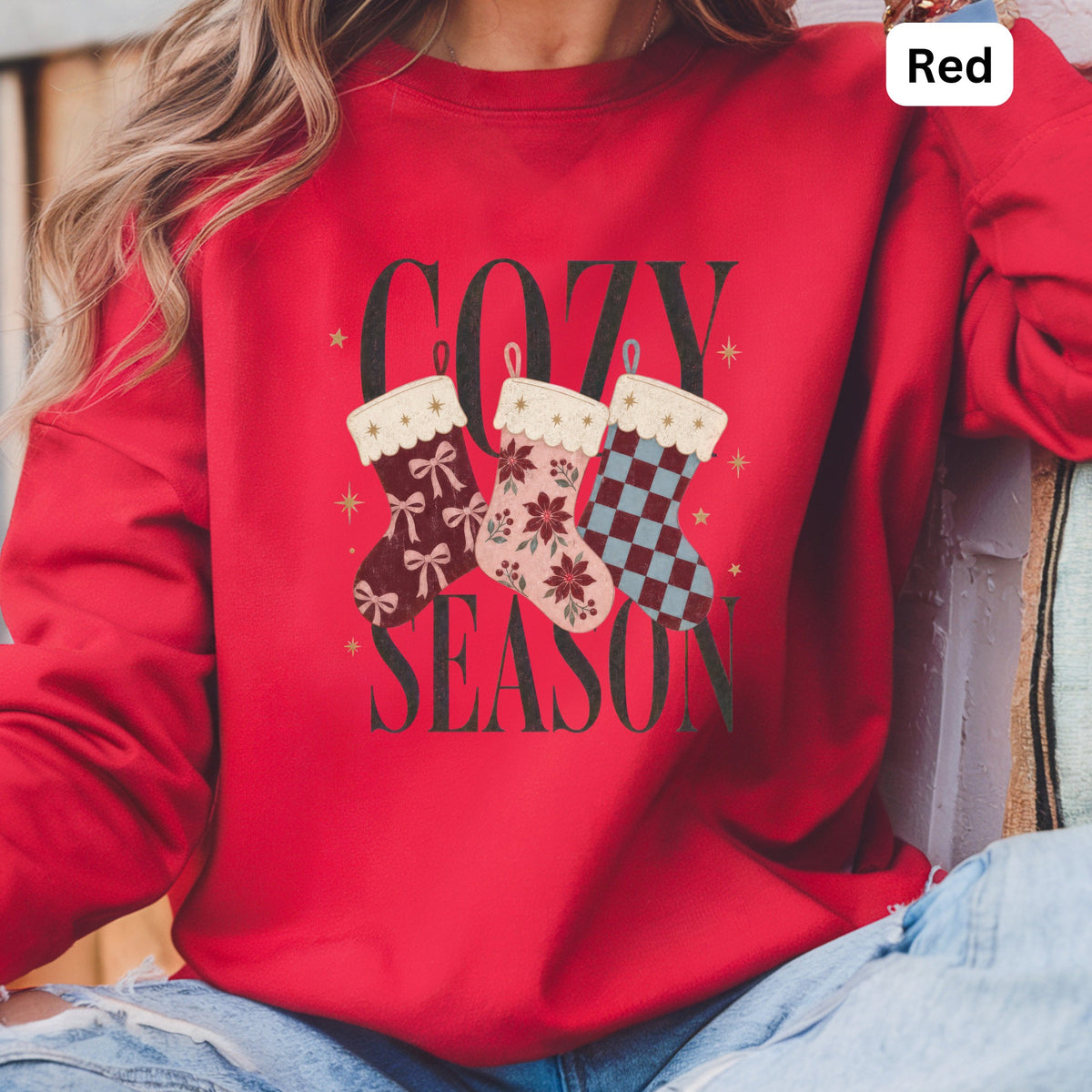 Red sweatshirt with "COZY SEASON" and three decorated Christmas stockings.