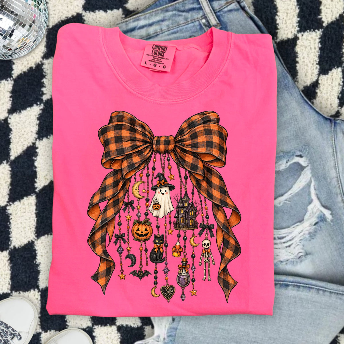 Pink t-shirt with orange and black plaid bow and Halloween charms.
