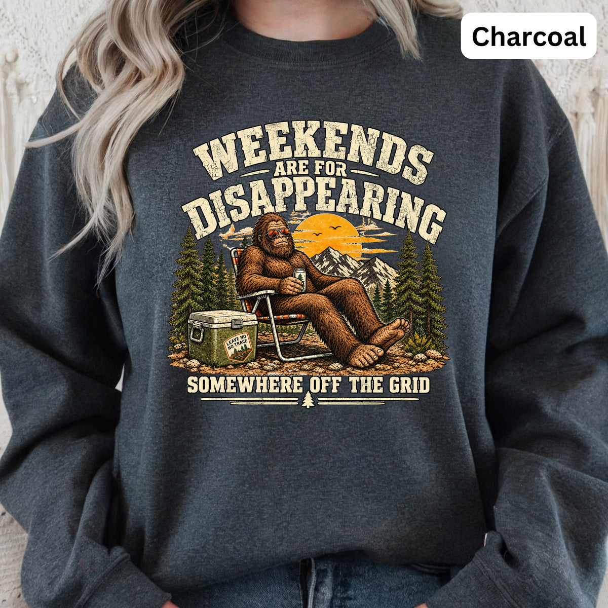 Bigfoot relaxing with cooler and mountains, text "Weekends are for disappearing somewhere off the grid".