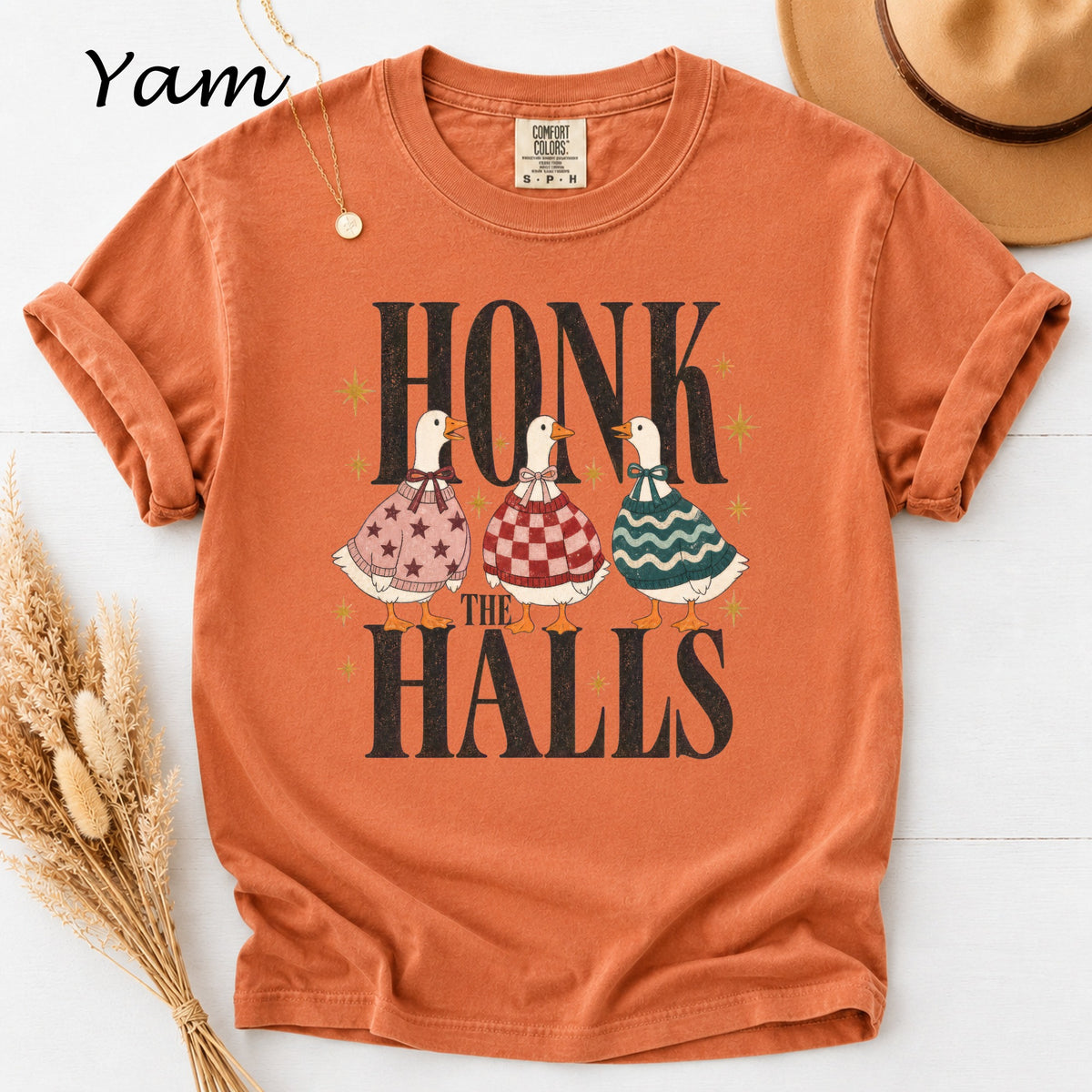 Orange t-shirt with three geese wearing sweaters and text "Honk the Halls".
