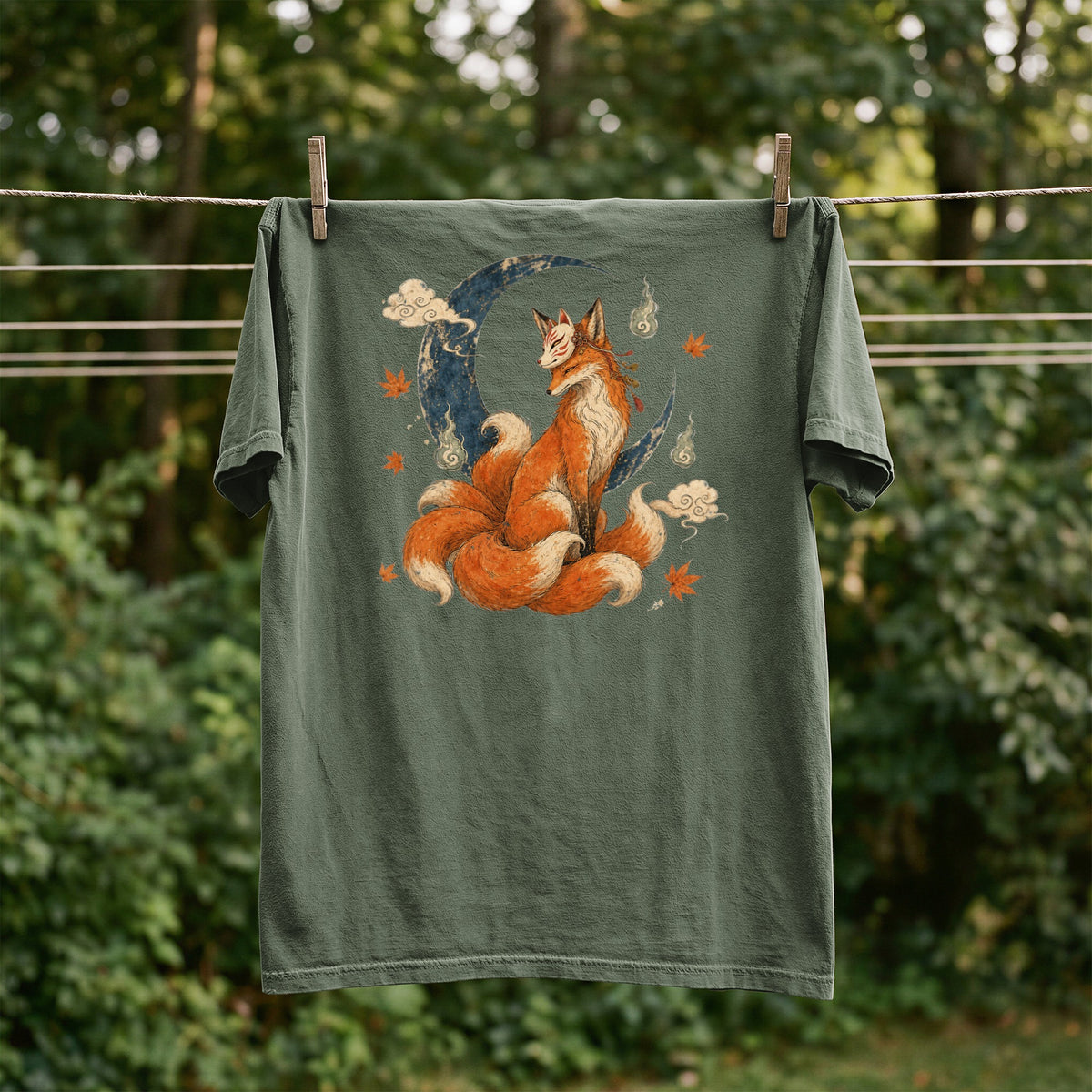 Green t-shirt with a nine-tailed fox wearing a mask sitting on a crescent moon.