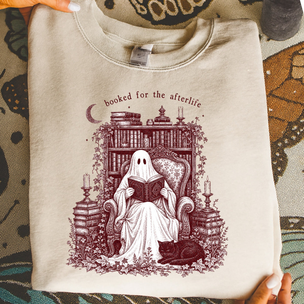 Ghost reading a book in armchair by bookshelf, with text "booked for the afterlife".
