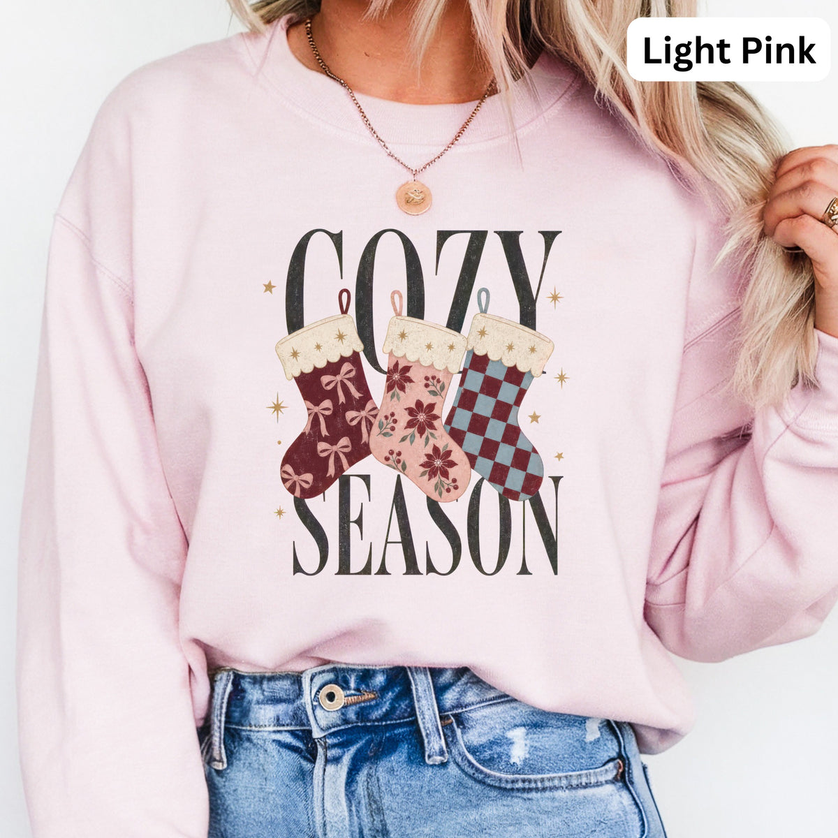 Light pink sweatshirt with "Cozy Season" text and three Christmas stockings.