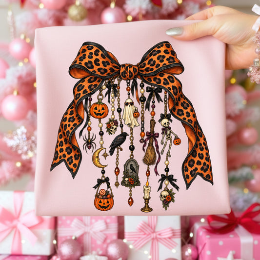 Leopard print bow with hanging Halloween charms on pink fabric.