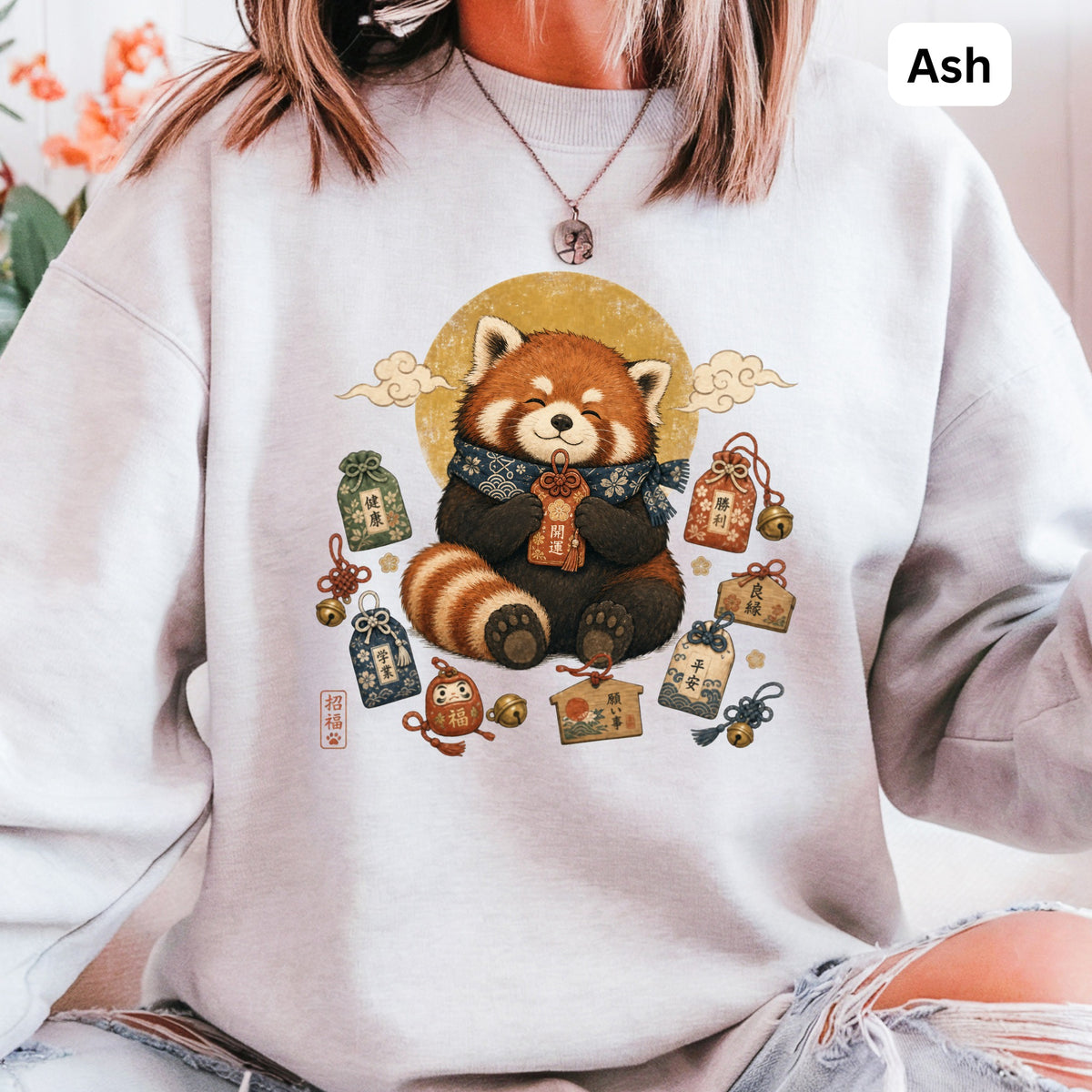 Red panda wearing scarf surrounded by good luck charms and Japanese text.