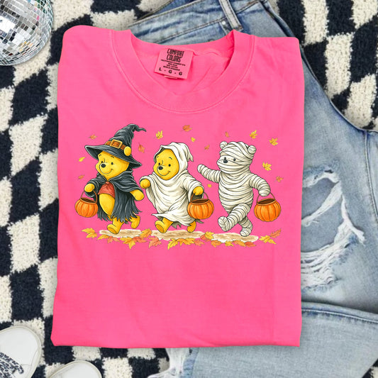 Winnie the Pooh characters dressed as a witch, ghost, and mummy on a pink shirt.
