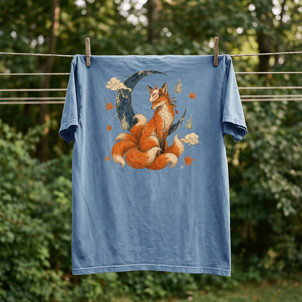Blue t-shirt with a nine-tailed fox sitting on a crescent moon with clouds.