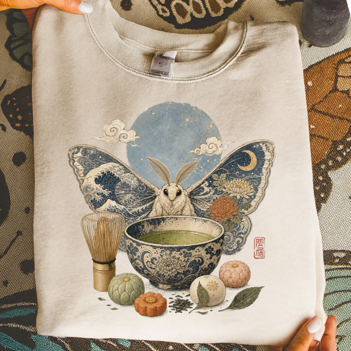Cream sweatshirt with moth, matcha bowl, whisk, and mooncake illustration.
