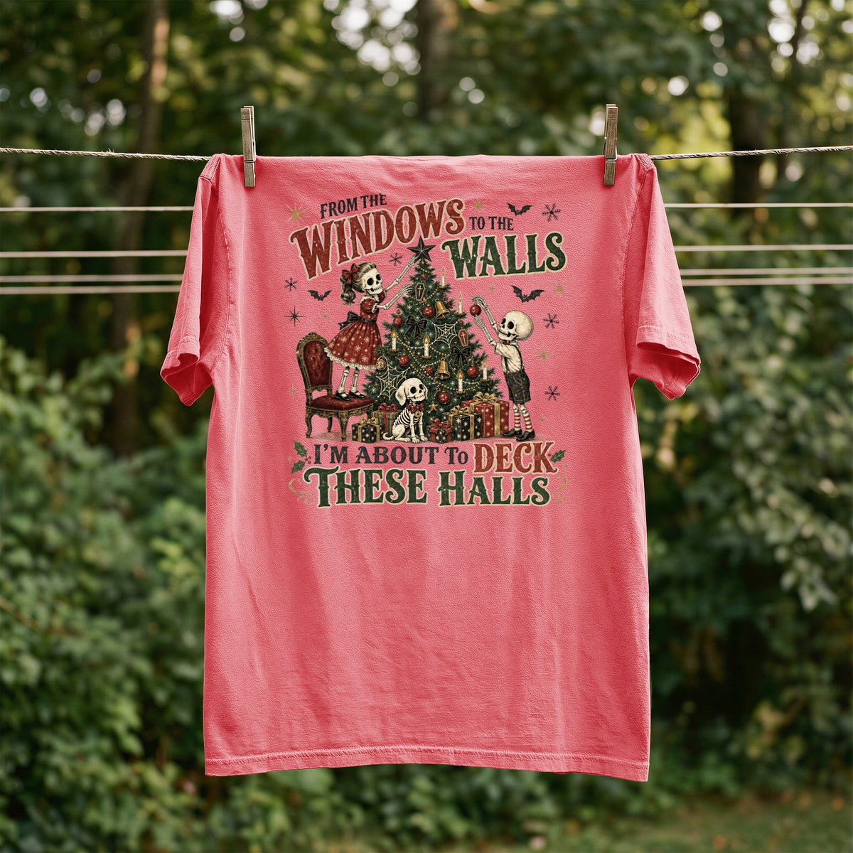 Coral t-shirt with skeleton family decorating a Christmas tree and text.