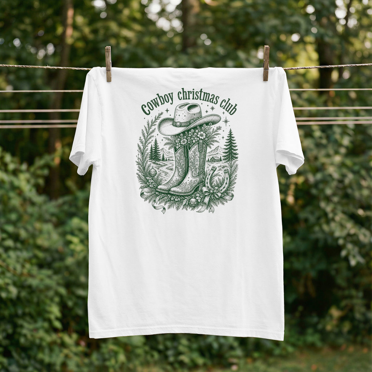 White t-shirt with "Cowboy Christmas Club" text, cowboy hat, boots, and wreath graphic.